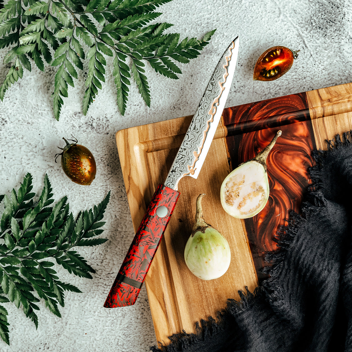 Cuchillo Utilitario 13cm 10Cr+Lluvia Cobre Damasco54 Resina Roja y Carbono con higo cortado y tomate del arbol sobre tabla de madera y resina