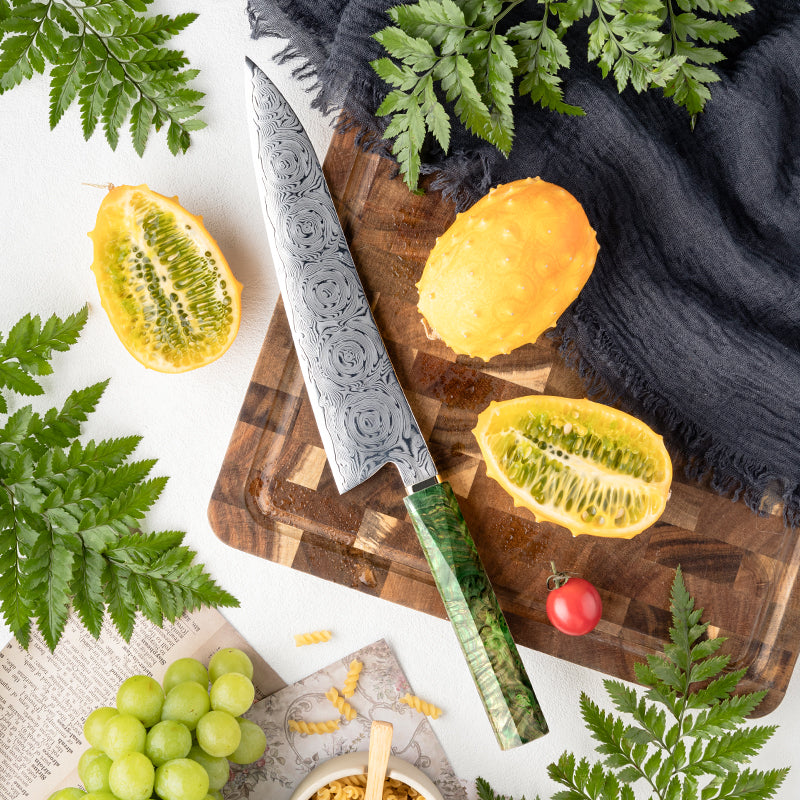 Cuchillo de Chef 22cm 10Cr+Rosa Damasco66 Madera EST Verde y Cobre, sobre una tabla de picar.