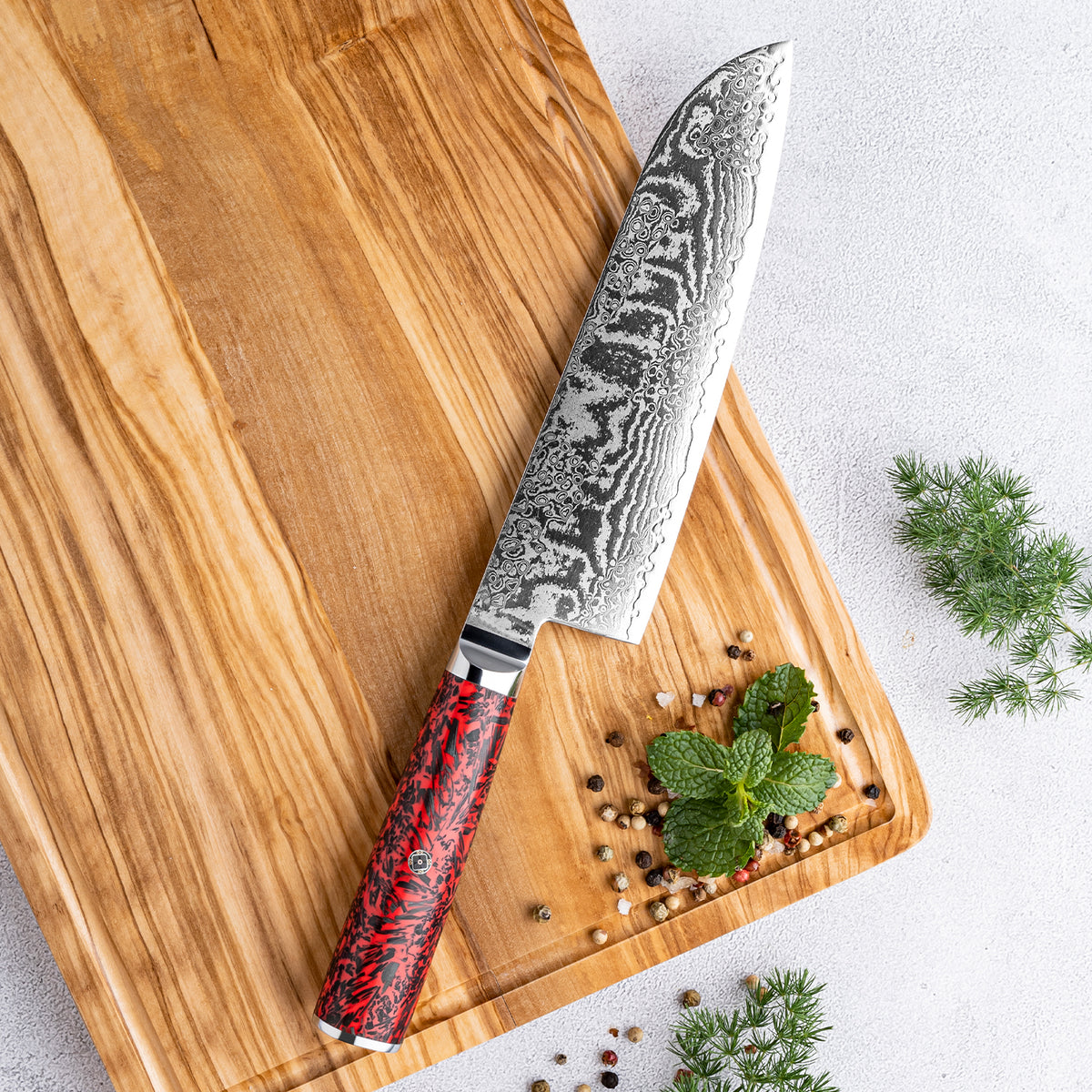 Cuchillo Santoku 18cm S35VN+Ola Damasco66 Resina Roja y Carbono sobre una tabla de picar.