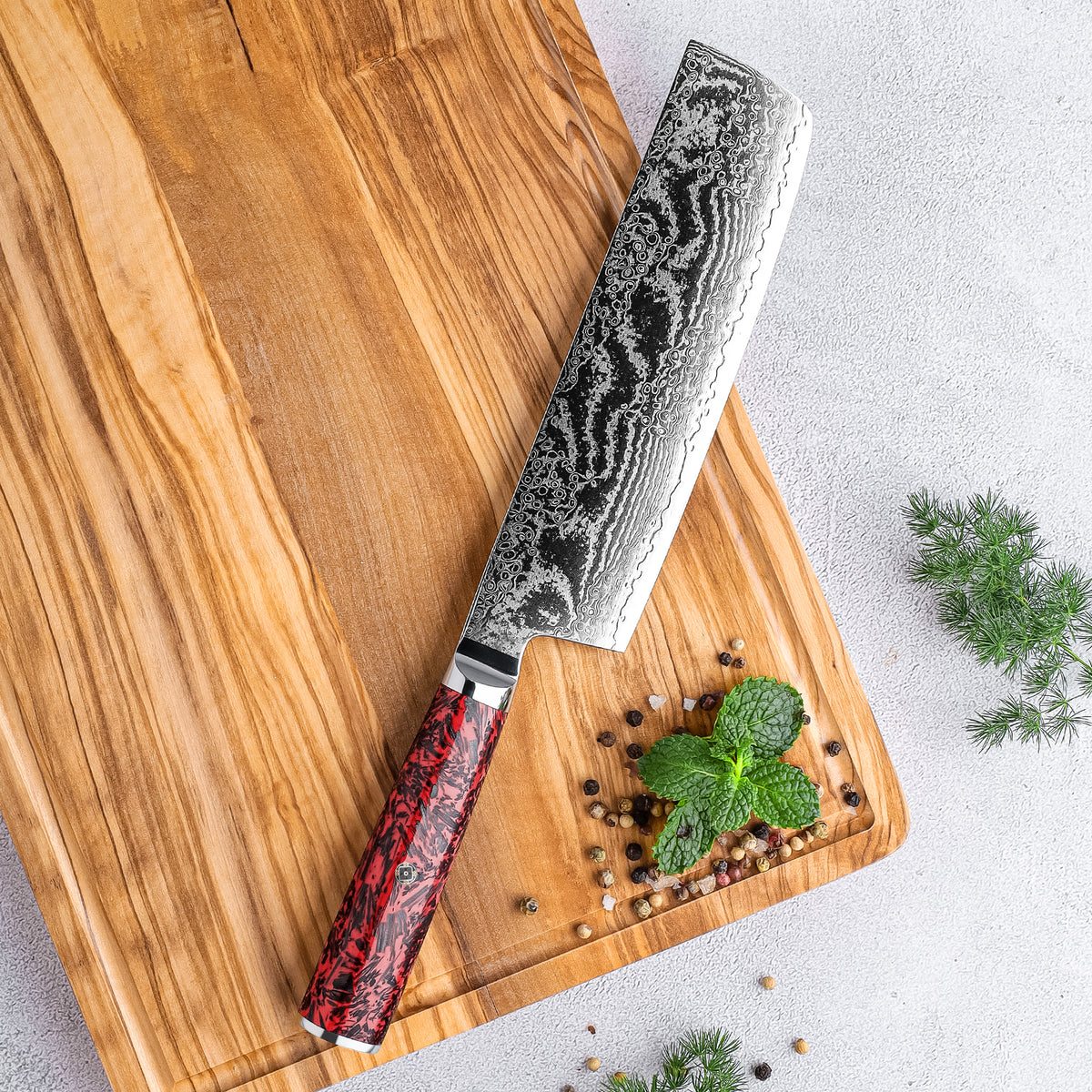 Cuchillo Nakiri 18cm S35VN+Ola Damasco66 Resina Roja y Carbono, sobre tabla de madera veteada y hierbas aromaticas, pimienta roja