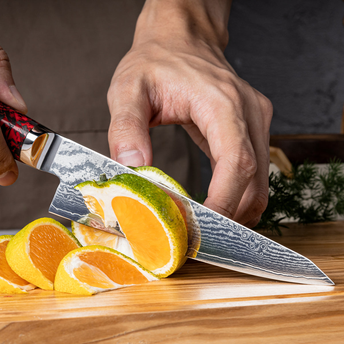 Cuchillo Utilitario 15cm S35VN+Ola Damasco66 Resina Roja y Carbono, cortando unas naranjas.