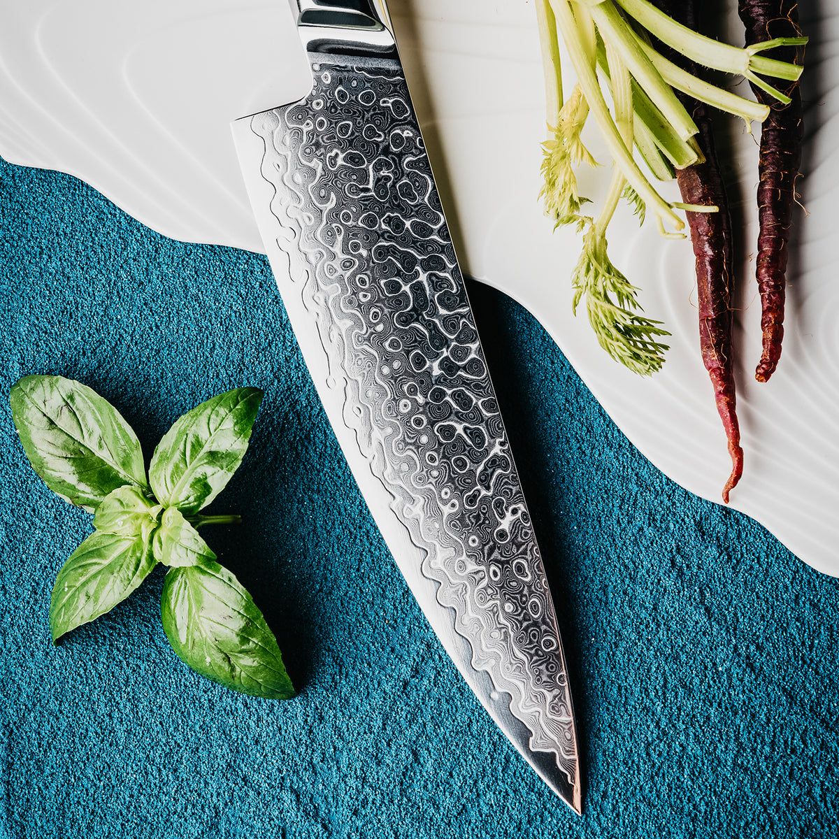 Cuchillo de Chef 20cm 10Cr+Gotas Damasco128 Full Tang Resina Azul, acompañado con hojas de albaca y raices de verduras