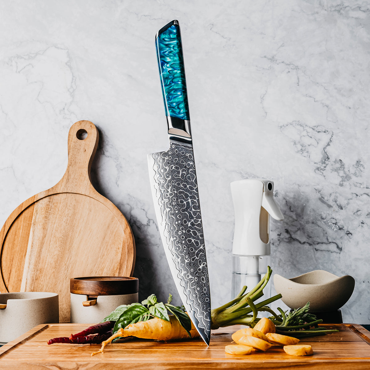 Cuchillo de Chef 20cm 10Cr+Gotas Damasco128 Full Tang Resina Azul, cuchillo centrado, sobre tabla de picar, acompañado de verduras.