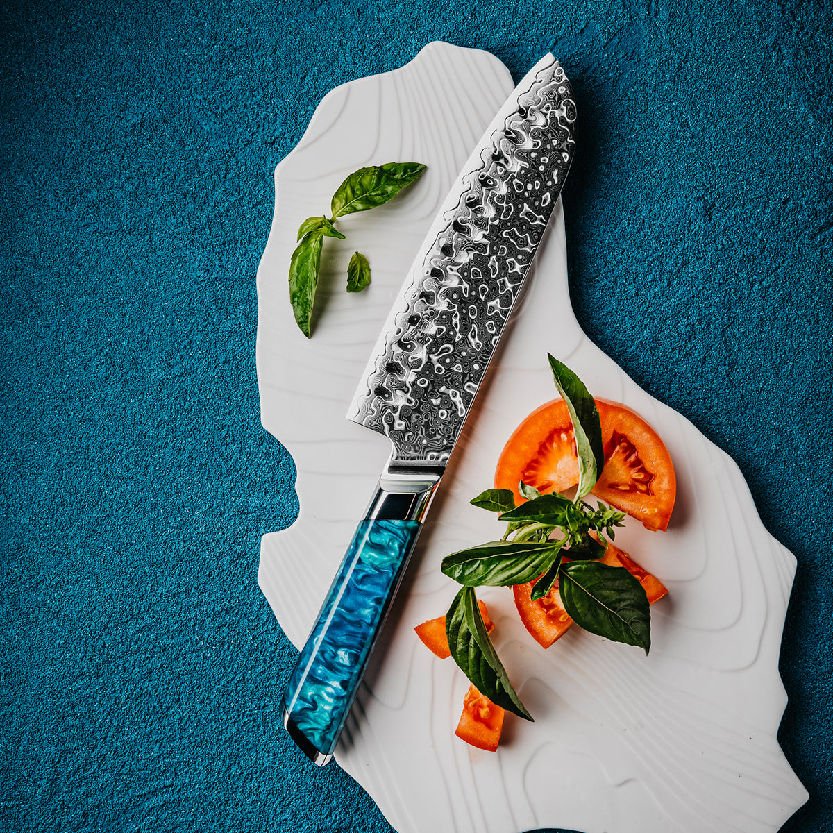 Cuchillo Santoku 18cm 10Cr+Gotas Damasco128 Full Tang Resina Azul, cuchillo centrado, con fondo azul.