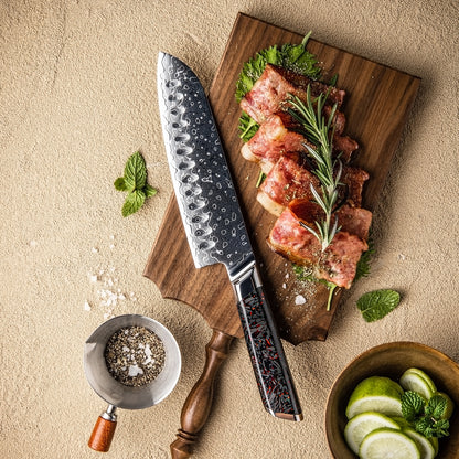Cuchillo Santoku 18cm 10Cr+Gotas Damasco128 Full Tang Resina Carbono, sobre una tabla de picar, acompañado de tocino y especias.